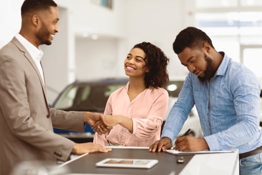 Buying Car. Black Couple Shaking Hands With Salesman And Signing Papers In Cars Selling Center. Selective Focus photo