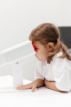 A young girl engages in orthoptic and pleoptic therapy using advanced vision stimulation equipment. Laser eye treatment promotes recovery and enhances vision in a soothing environment photo
