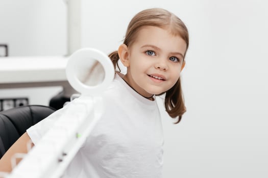 A little girl enjoys an engaging vision game on state-of-the-art ophthalmic equipment. The Rainbow system enhances eyesight in a comfortable and welcoming environment. photo