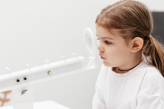 A little girl enjoys an engaging vision game on state-of-the-art ophthalmic equipment. The Rainbow system enhances eyesight in a comfortable and welcoming environment. photo