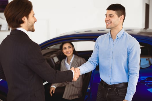 Successful Deal. Sales manager handshaking with happy auto buyer man in dealership store, selective focus photo