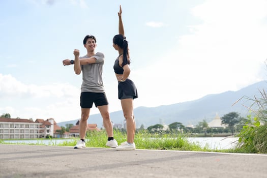 A sporty Asian couple in sportswear is stretching and warming up before running together in a park. photo