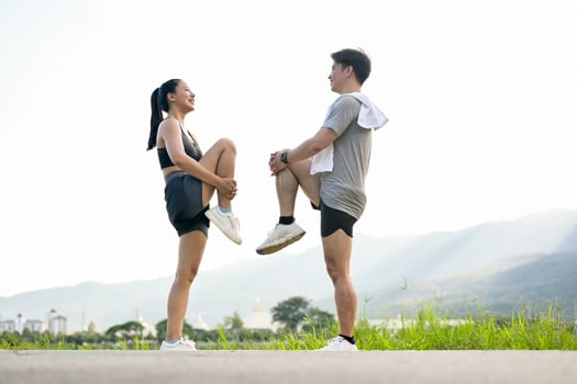 An active, sporty Asian couple in sportswear is stretching their legs, warming up before running. photo