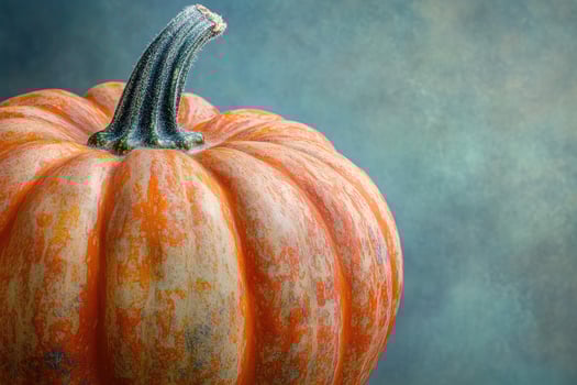 Close-up of an orange pumpkin with a green stem against a blue-green background. photo