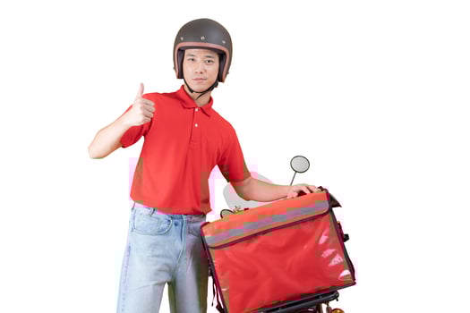 Cheerful young delivery man stands casually beside a red motorcycle photo