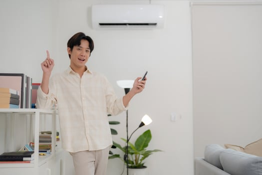 Young man using smart thermostat app in modern living room photo