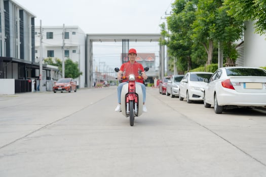Delivery rider on red motorbike with insulated food box parked outdoors photo