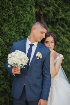 A bride and groom are hugging each other while holding a bouquet and a bouquet photo