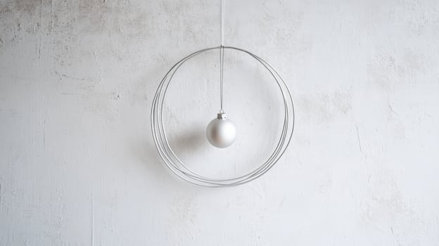 Silver Christmas Ornament Hanging in a Wire Circle Against a White Wall photo