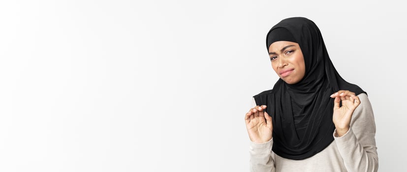 Disgusted black muslim woman in hijab feeling aversion about something, taking hands, posing over light background in studio, free space photo