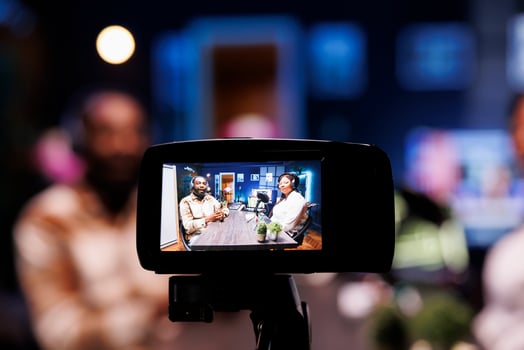 Focus on vlogging camera used by cohosts in blurry background streaming podcast during live debate on vlog channel. Close up of professional recording gear used by man and woman in studio to film show photo
