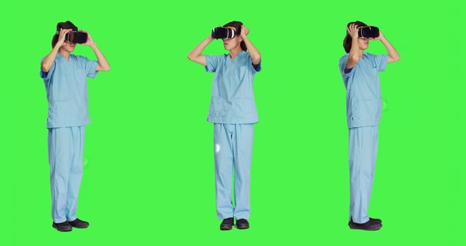 Young nurse using virtual reality headset against greenscreen backdrop, working with modern interactive 3d glasses. Medical healthcare assistant working with artificial intelligence. photo