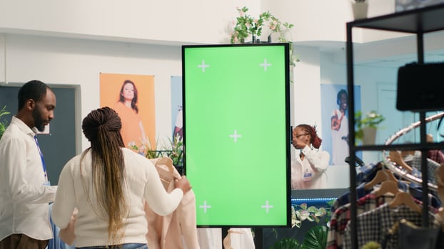 Green screen kiosk in luxury clothing shop advertising new collection of elegant formalwear clothes. Chroma key mockup digital display in fashion boutique used to promote store garments photo