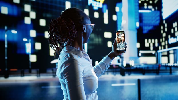 African american woman talking with friend in online videocall while strolling around dimly illuminated empty city avenues at night, keeping herself busy to feel safe while walking alone photo