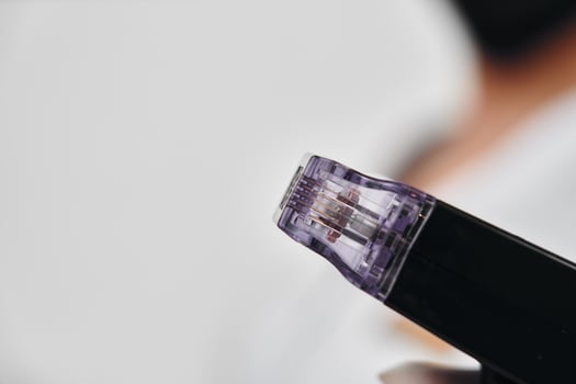 Close-up view of a microneedling device being held in a clinic setting photo