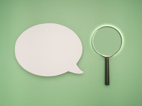 Top view of a blank speech bubble and a magnifying glass on a green background photo