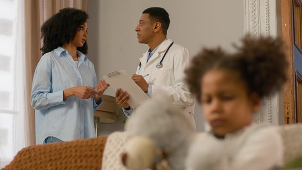 African American mother consulting communicate talk explain doctor sad little girl illness unwell sick child hug soft toy teddy bear healthcare patient pediatrician family medicine daughter physician photo