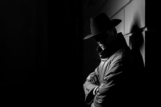 dark silhouette of a man in a raincoat with a hat at night photo
