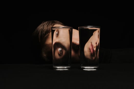 strange portrait of a man looking through two glasses of water photo