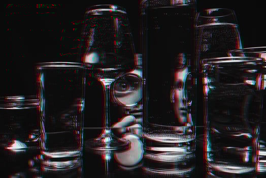 man looking through a magnifying glass and glasses of water with reflections and distortions photo