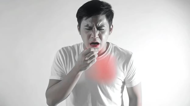 A man coughs, covering his mouth with his hand. He has a red area on his chest, suggesting he is sick. photo