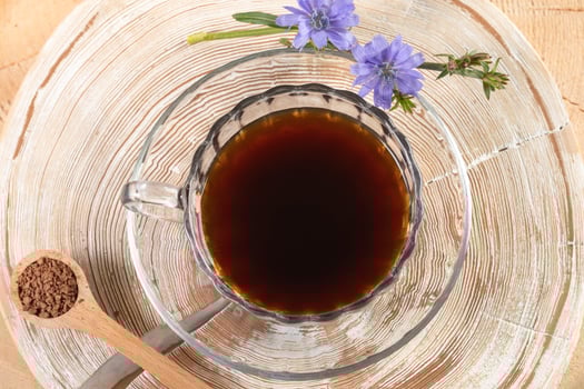 Healthy soluble granulated chicory tea in glass cup on wooden stump with annual rings close up. photo
