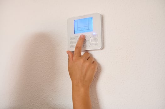 Hand adjusting temperature on modern digital thermostat at home photo