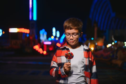 A cute Caucasian boy, a child, came to the amusement park to have fun, play and ride a merry-go-round. A child standing in front of a merry go round photo