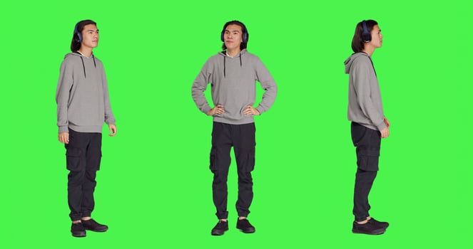 Person listening to audio music and dancing around studio with headphones, having fun with songs and groovy dance moves. Cheerful man feeling lovely and funky, full body greenscreen. photo