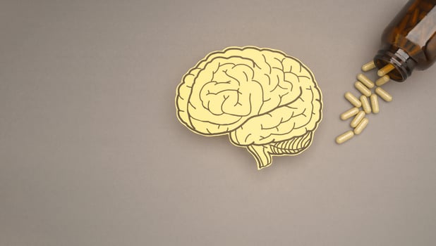 Brain shape made from paper and pills capsules with a bottle on a gray background photo