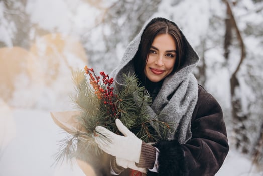 Portrait of happy pretty woman holding winter pine bouquet and posing in snowy forest photo
