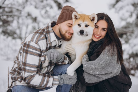 Happy young couple walking with akita dog in forest on winter and snowly day photo