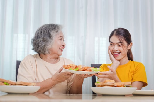 Mother and adult daughter eating meal together, Senior woman and daughter having breakfast in morning together photo
