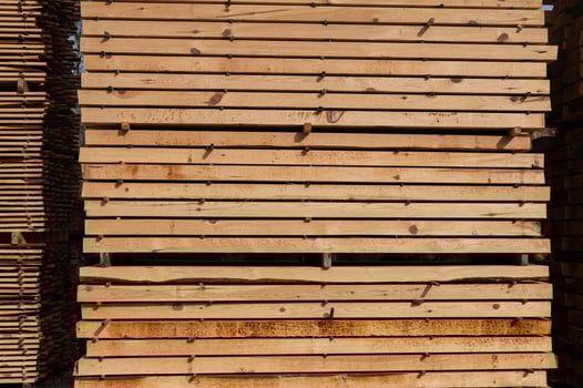 Stacks of boards, board flooring in a sawmill. Warehouse for cutting boards in a sawmill outdoors. Stack of wooden blanks construction material wood timber. Industry. photo
