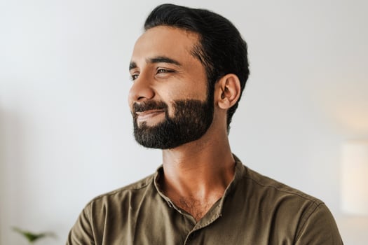 Portrait of handsome bearded indian man smiling and looking away closeup photo