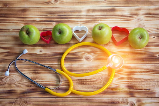 Green apple and small heart on wooden board photo