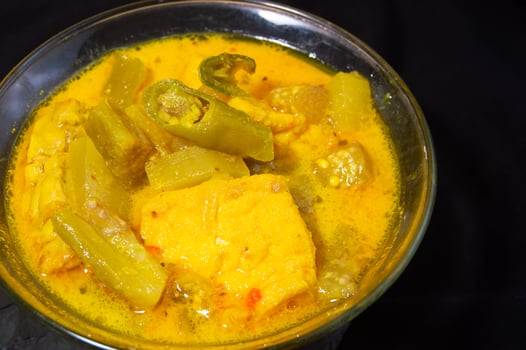 sayur lodeh in a bowl on a black background. Sayur lodeh is a typical Indonesian vegetable dish made from coconut milk. photo