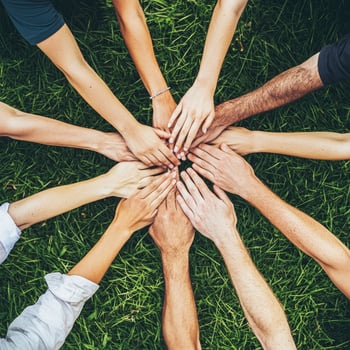group of people from various backgrounds gathers in an outdoor park connecting by holding hands to signify unity and togetherness in a natural setting. photo