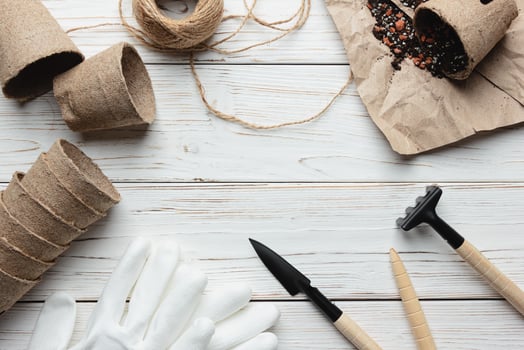 Gardening. Tools for garden and eco pots with ground on white wooden background. photo