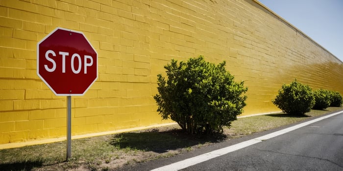 A stop sign is in front of a yellow wall photo