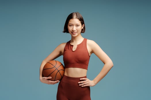 Smiling sportswoman holding ball, looking at camera, isolated photo