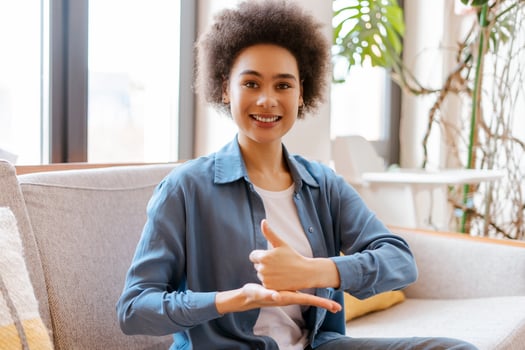Smiling beautiful African American woman with curly hair gesturing, communicating with sign language photo
