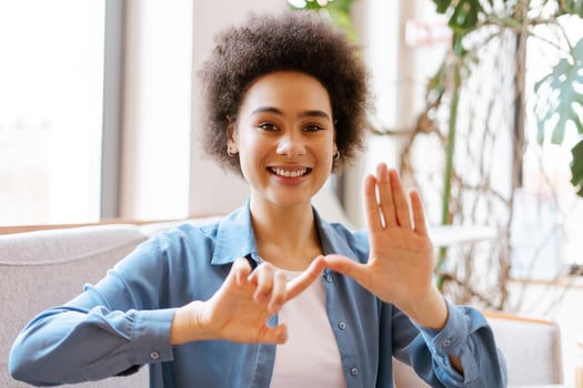 Attractive young African American woman with curly hair gesturing, communicating with sign language photo