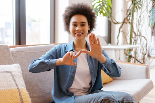Smiling African American curly haired woman wearing casual clothes communicating with sign language photo