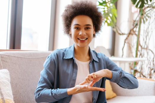 Portrait authentic, smiling African American woman with curly hair communicates using sign language photo