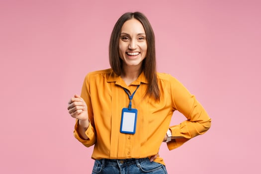 Smiling pretty young woman posing in studio with accreditation card on the neck photo