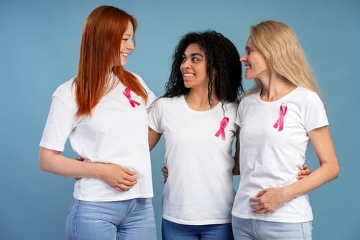 Diverse group of women embracing and showing pink ribbons for breast cancer awareness photo