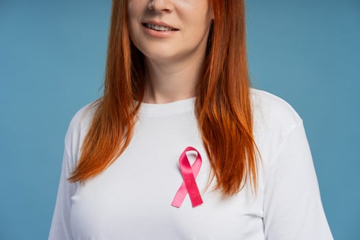 Smiling redhead woman wearing pink ribbon showing support for breast cancer awareness photo