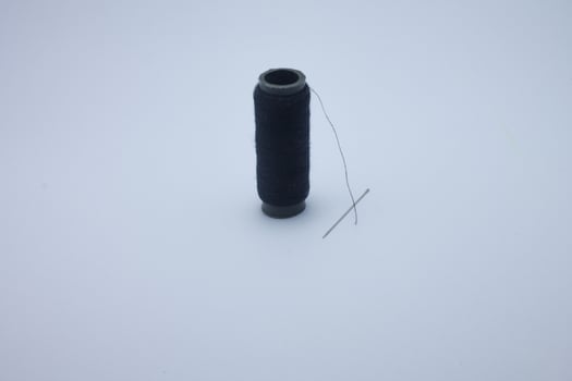 isolated spool of black thread and sewing needle photo