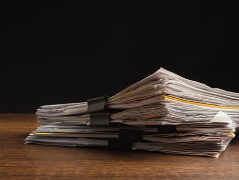 Stack of documents with binder clips on a wooden table with a black background photo